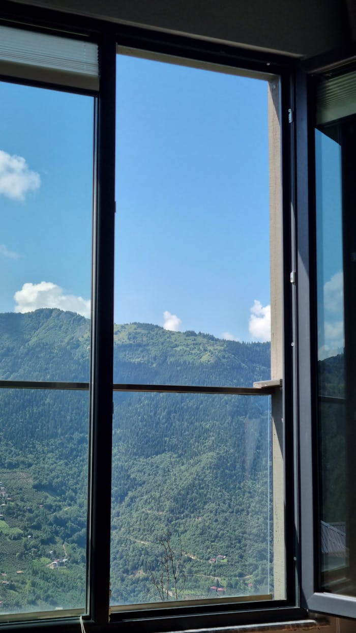 Breathtaking view of lush mountains through an open window on a sunny day.