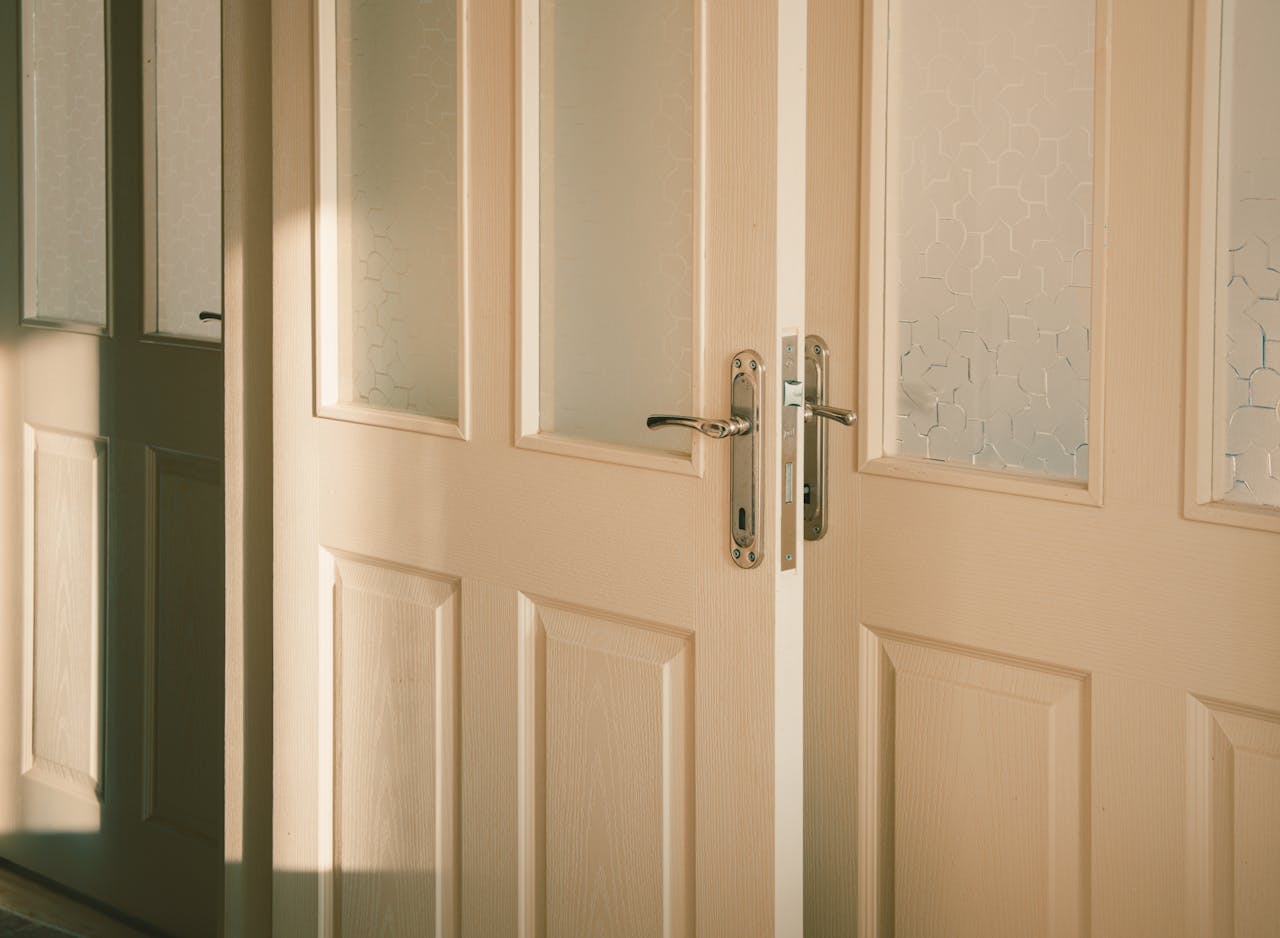 Elegant wooden doors with frosted glass panels softly illuminated by streaming sunlight.